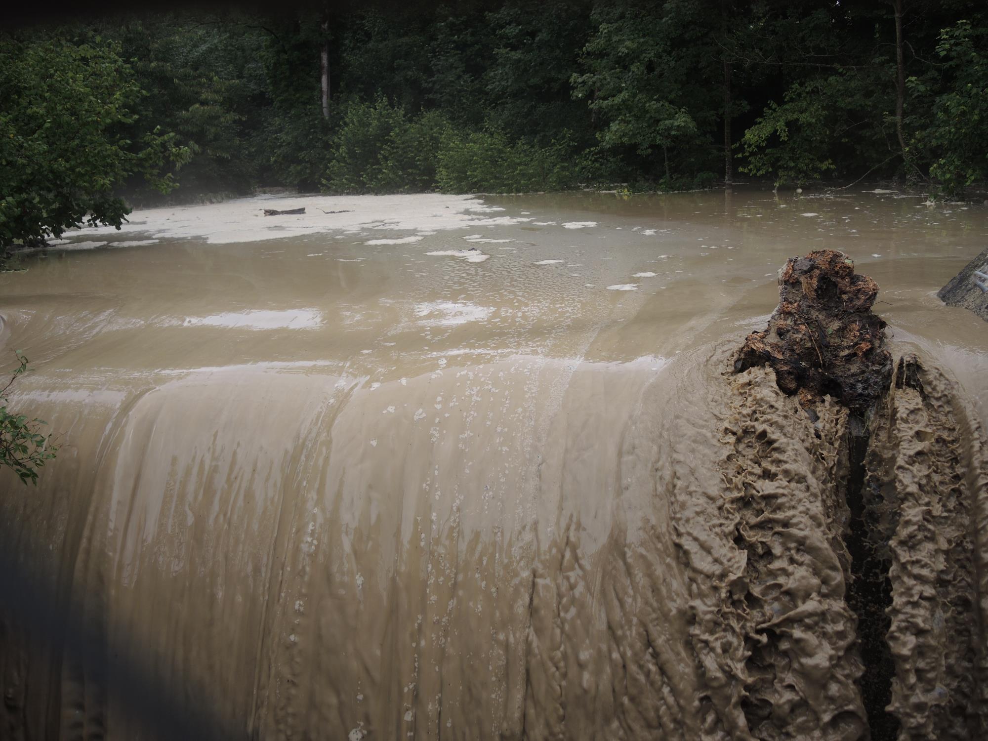 Überlaufendes Rückhaltebecken bei der Brücke Goldschrütifeld, mit Baumstrunk auf der Mauerkrone. Foto Josef Stirnimann-Maurer