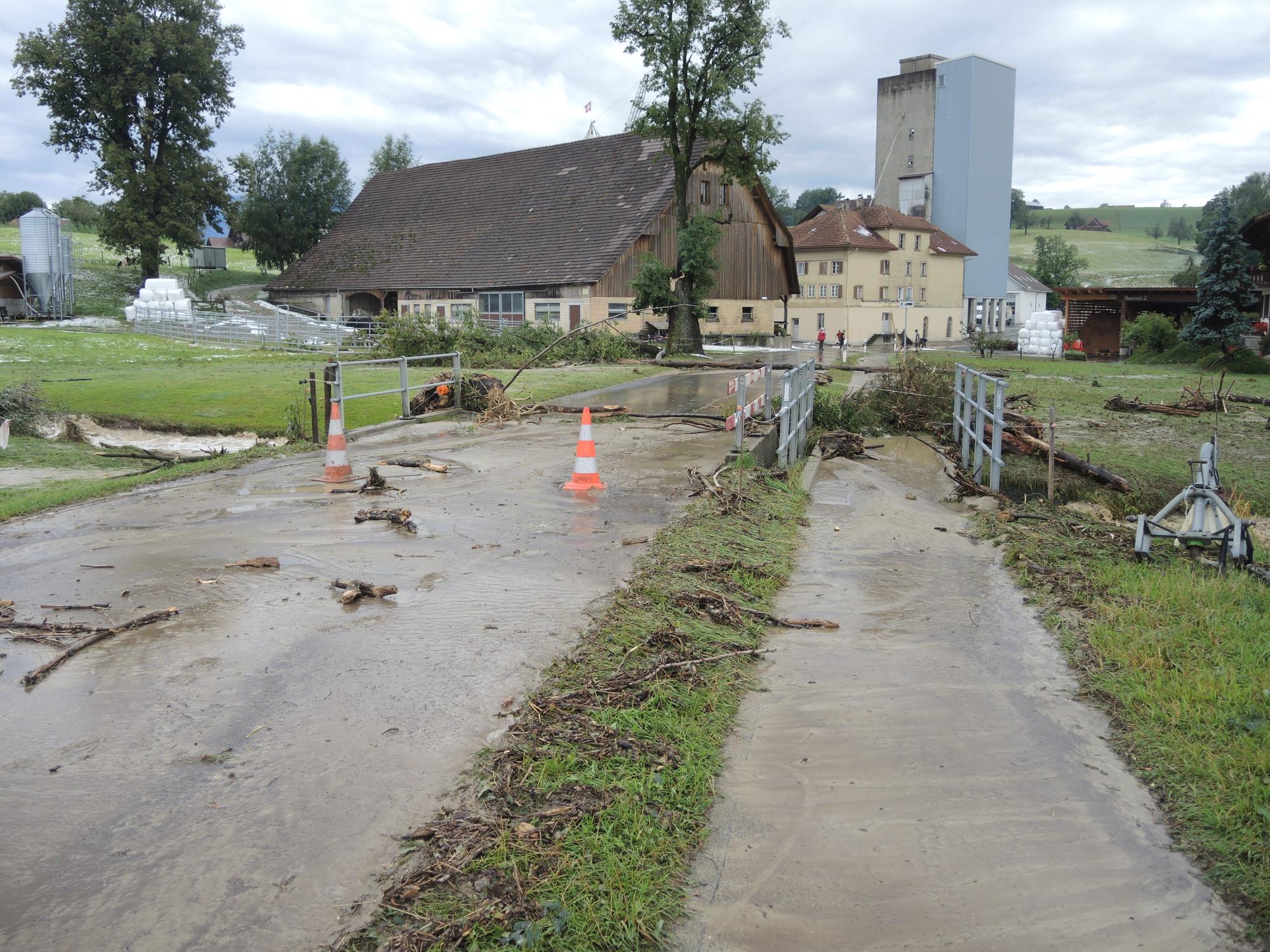 Neumühle nach dem Wasserhöchststand. Schwemmholz und ein abgebrochener Baumast liegen quer über der Strasse. Foto Josef Stirnimann-Maurer